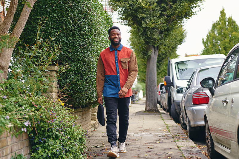 Een man maakt glimlachend een wandeling door zijn straat, een makkelijke manier om meer te bewegen